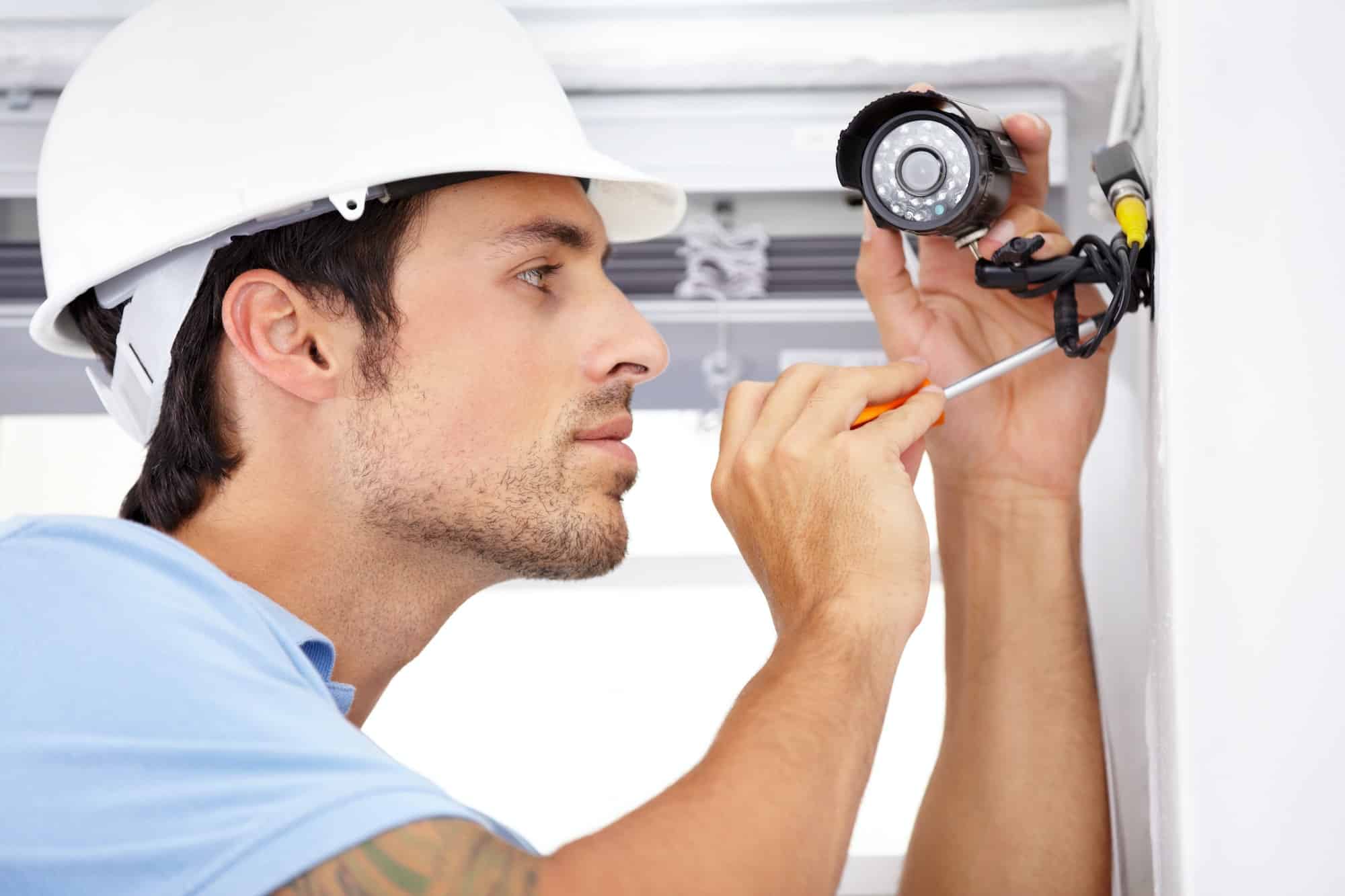 Shot of a handsome young man installing a security camera