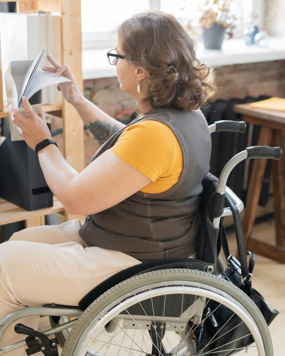 Young disable female office worker in casualwear looking through papers Young disable female office worker in casualwear looking through papers